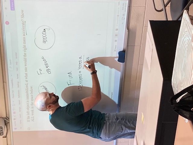 Instructor writing on whiteboard Instructor writing on a whiteboard with class materials projected onto it