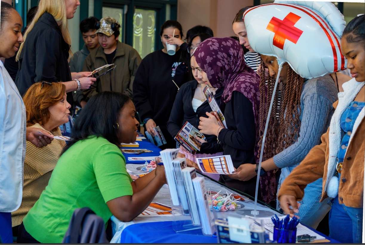Staff and students at an event table with flyers and merchandise