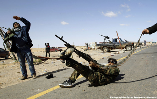 A rebel fighter fires his rifle at a military aircraft loyal to Col. Muammar Gaddafi at a checkpoint in Ras Lanuf March 7, 2011.